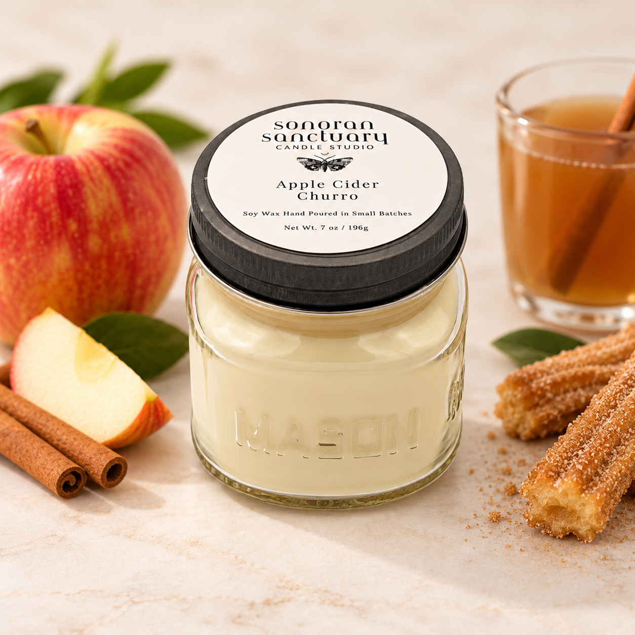 Sonoran Sanctuary Apple Cider Churro kitchen soy candle in a glass mason jar with black lid, styled with red apples, cinnamon sticks, apple cider and cinnamon-sugar churros