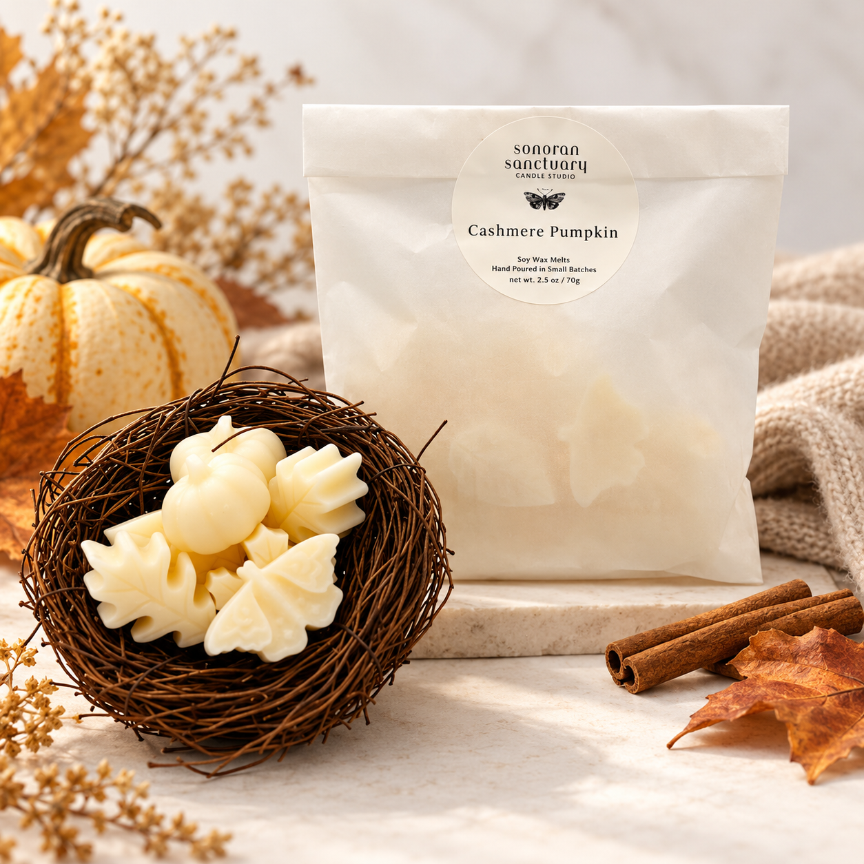 Sonoran Sanctuary Cashmere Pumpkin wax melts in branded packaging with botanical-shaped wax melts, decorative pumpkin, cinnamon sticks and autumn leaves