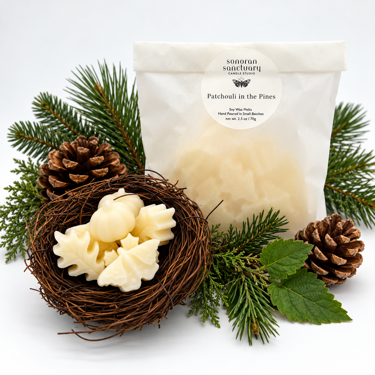 Sonoran Sanctuary Patchouli in the Pines wax melts in branded packaging with botanical-shaped wax melts, fresh pine branches, evergreen foliage and pinecones